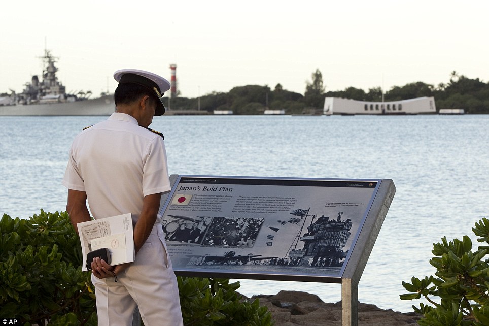 Anniversary: With the USS Arizona Memorial in the background, Japanese Maritime Self Defense Force Commander Seishi Goto reads a historical placard in Pearl Harbor, Hawaii, on Wednesday