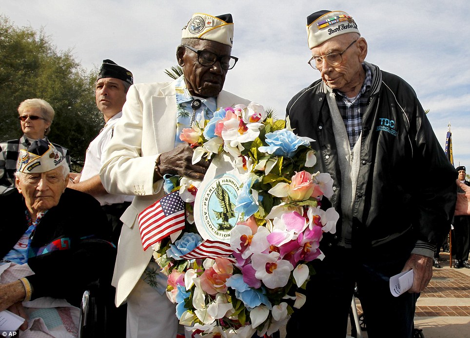 Together: Pearl Harbor survivors Marvin Rewerts, 89, right, Nelson Mitchell, 91, middle, walk with a wreath to place at the USS Arizona Memorial, as fellow survivor Darnel Rogers, 91, left, looks on, on Wednesday in Phoenix, Arizona