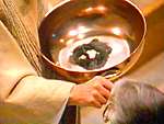 Priest anointing a member of the congregation with ashes from a large bowl