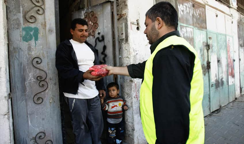 A man handing meat to a less fortunate family